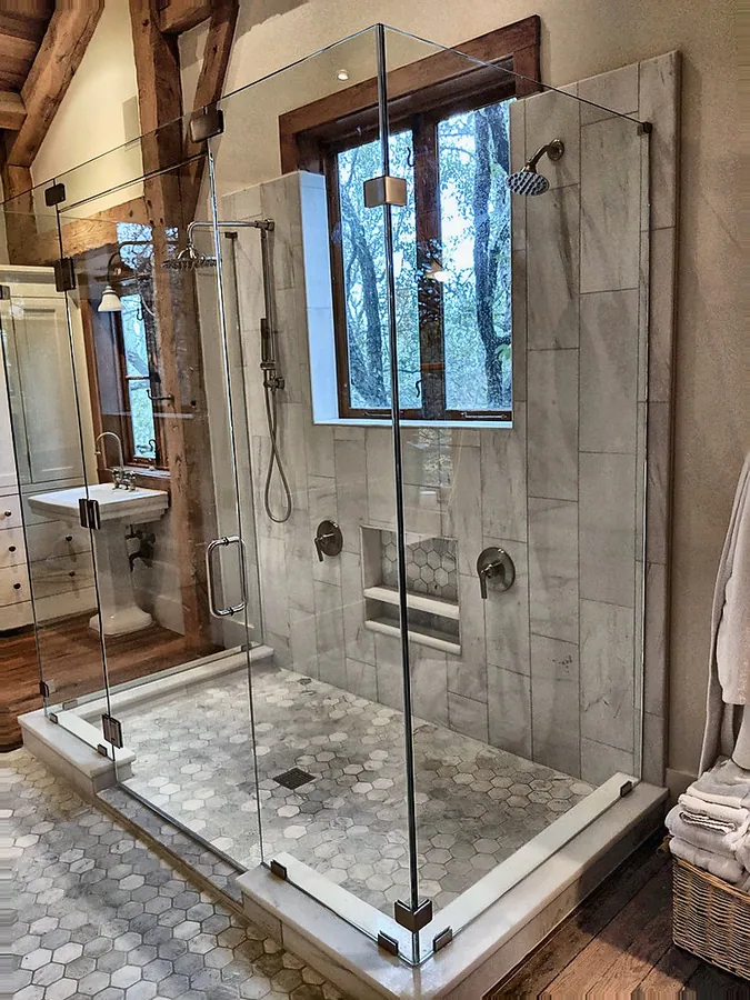 Stone and glass detailing in a spacious bathroom.