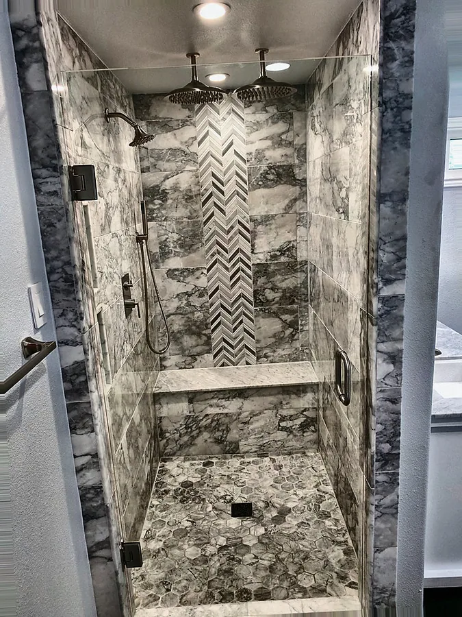 A walk-in shower with a herringbone tile focal wall.