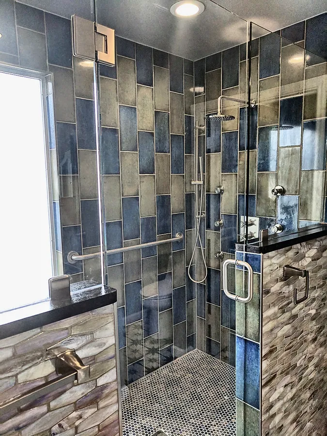 Geometric tile with clear glass shower panels.