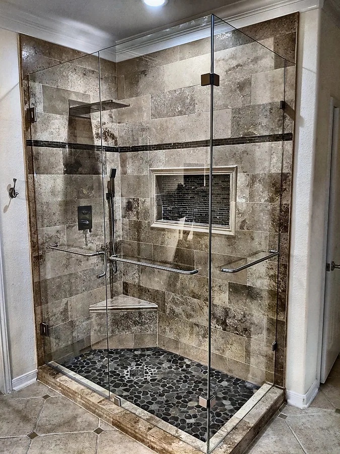 A glass-enclosed shower with contrasting stone textures.