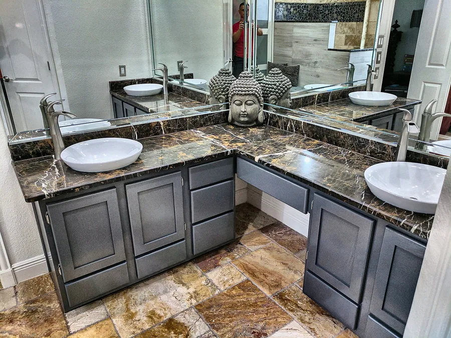 A double vanity with dark countertop and stone accent walls.