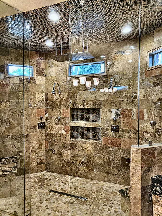 A spacious glass enclosure with warm-toned stonework.