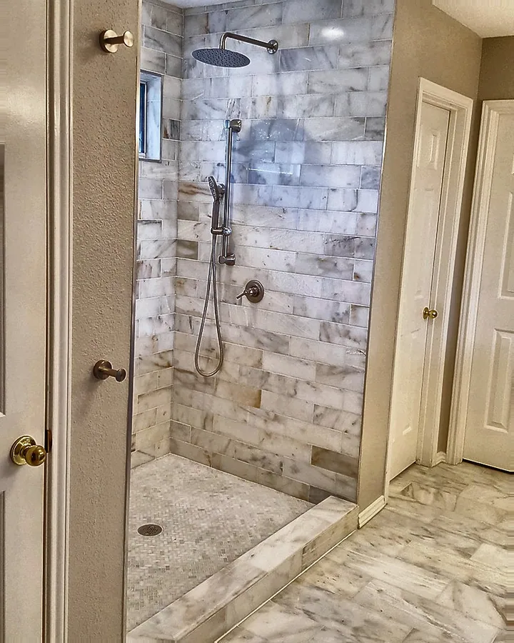 Light marble-look tile and a minimalist open shower design.