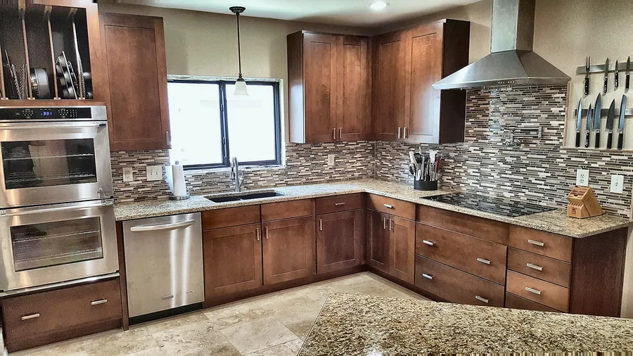 Wood cabinetry, stone countertops and layered backsplash details.