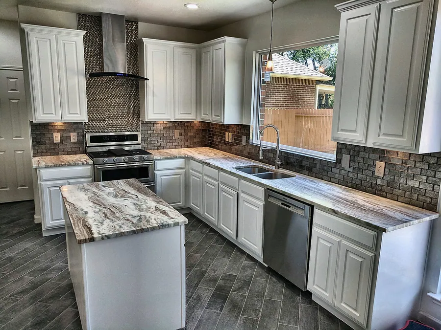 White cabinetry, detailed backsplash, and an expansive island.