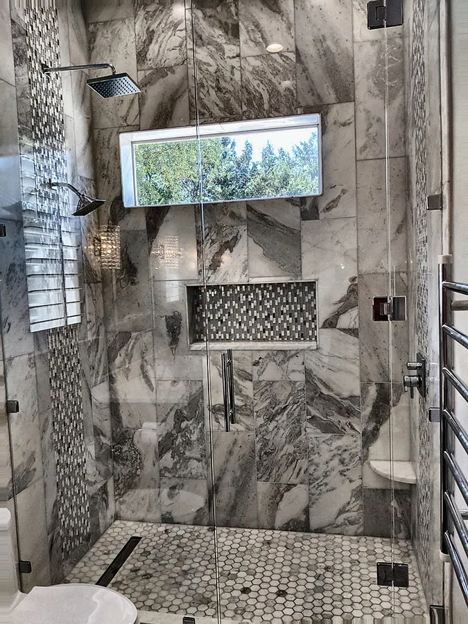 A walk-in shower finished with patterned stone-look tile.