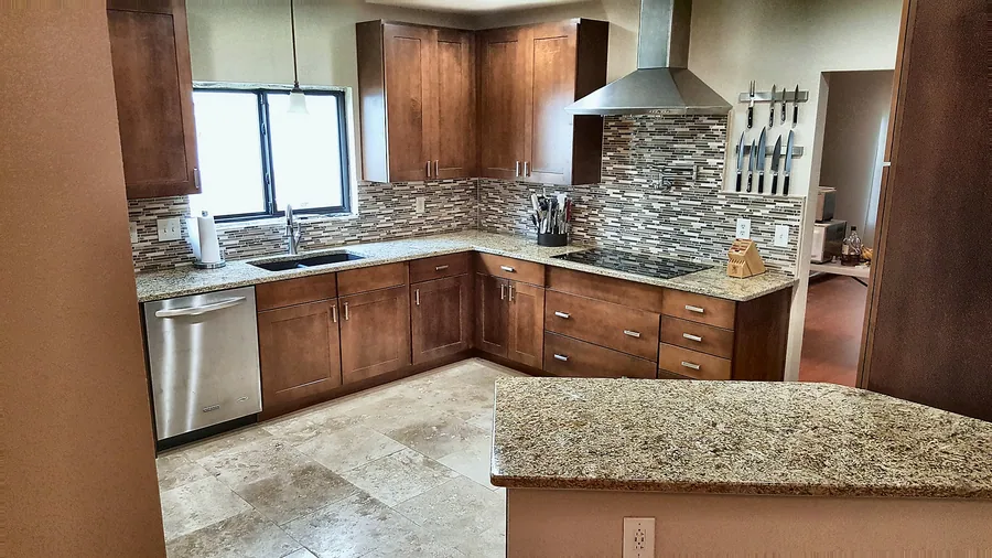 Natural wood kitchen with stone-look flooring and backsplash.