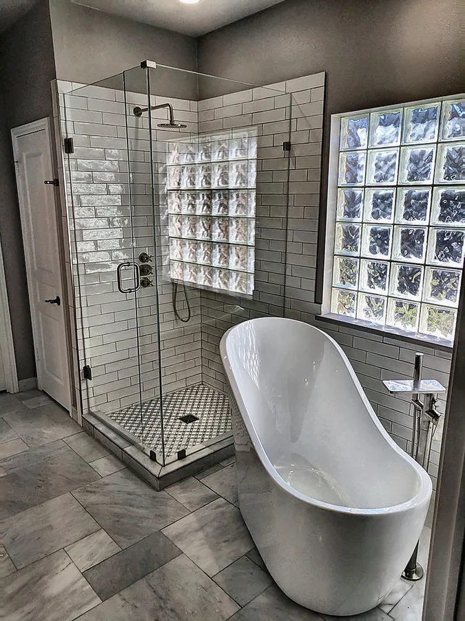 A bright bathing space with a freestanding tub and glass enclosure.