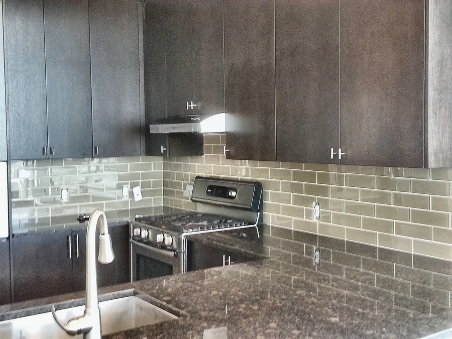 Dark cabinets with light tile backsplash and stainless steel.