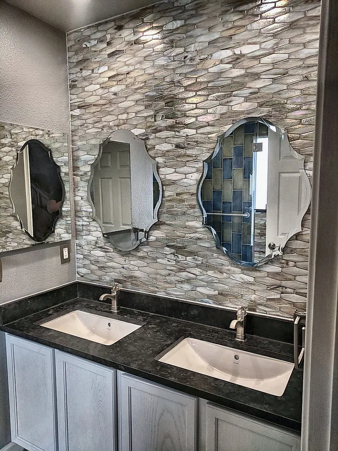 Stone accent wall with distinctive mirrors and dark countertops.