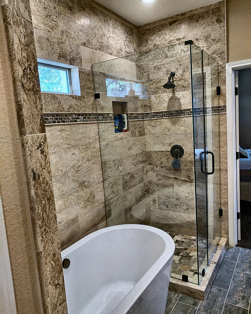 Stone-tiled bathroom with soaking tub and glass shower enclosure